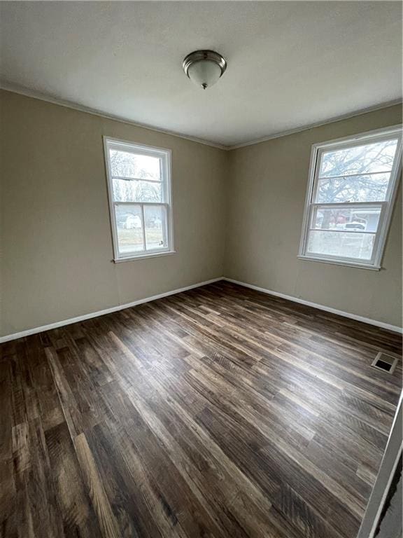 unfurnished room with dark wood-style floors, visible vents, and baseboards