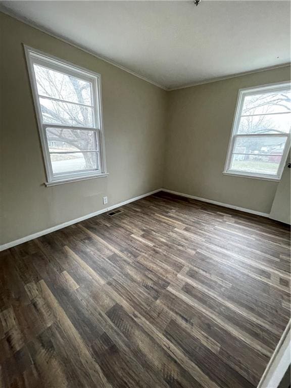 spare room featuring visible vents, baseboards, and dark wood-style flooring