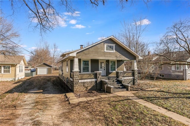 bungalow featuring a detached garage, an outdoor structure, covered porch, and driveway