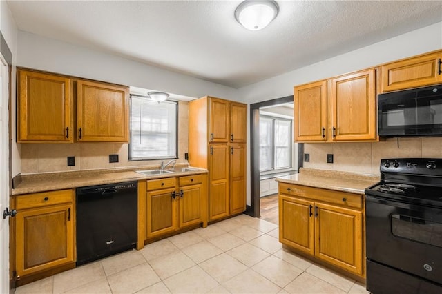 kitchen featuring brown cabinets, black appliances, and a sink