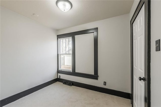 carpeted spare room featuring visible vents, a textured ceiling, and baseboards