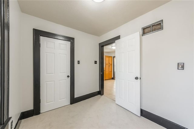 unfurnished bedroom with a textured ceiling, light colored carpet, visible vents, and baseboards