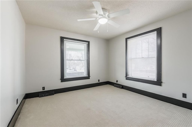 carpeted empty room featuring visible vents, baseboards, a textured ceiling, and ceiling fan