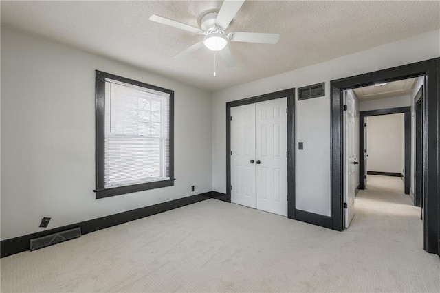 unfurnished bedroom featuring a closet, visible vents, light colored carpet, and a textured ceiling