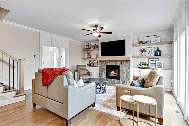 living room featuring stairs, visible vents, crown molding, and light wood finished floors