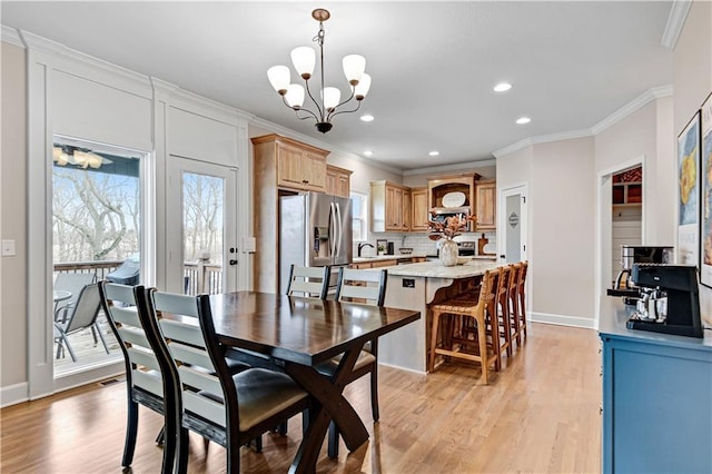 dining area featuring crown molding, a notable chandelier, baseboards, and light wood-type flooring