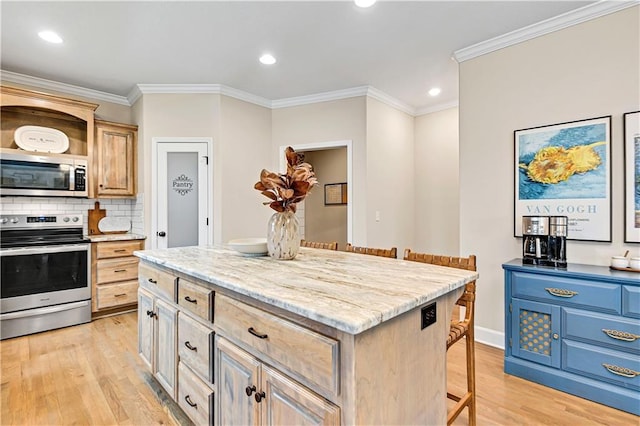 kitchen featuring a breakfast bar, ornamental molding, decorative backsplash, light wood-style flooring, and appliances with stainless steel finishes