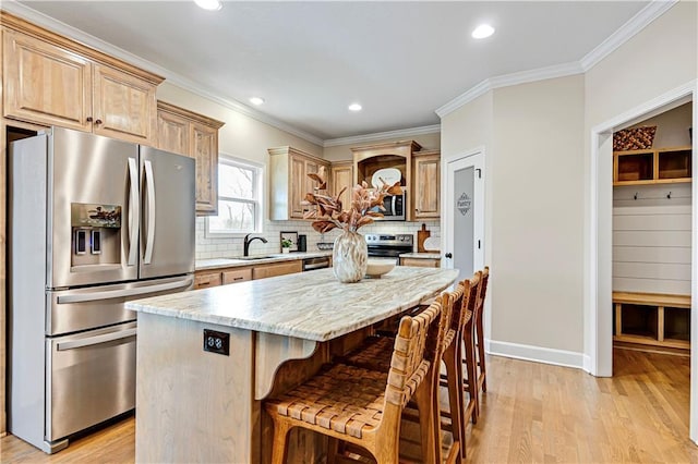 kitchen with light wood-type flooring, ornamental molding, appliances with stainless steel finishes, a kitchen breakfast bar, and tasteful backsplash