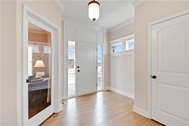 foyer with baseboards, crown molding, and light wood finished floors