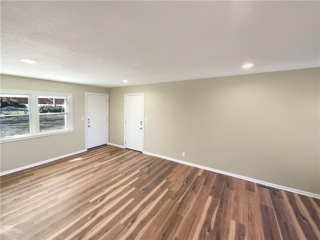 empty room with baseboards, wood finished floors, and recessed lighting