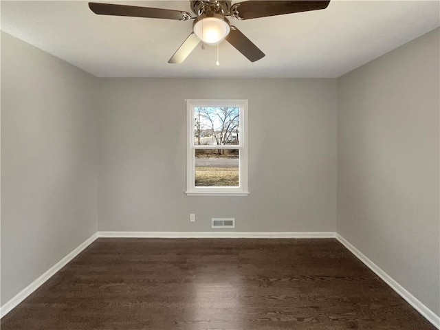 empty room featuring dark wood-style floors, visible vents, ceiling fan, and baseboards