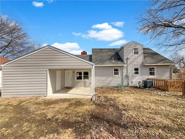 back of house with a shingled roof, a chimney, a patio area, and fence