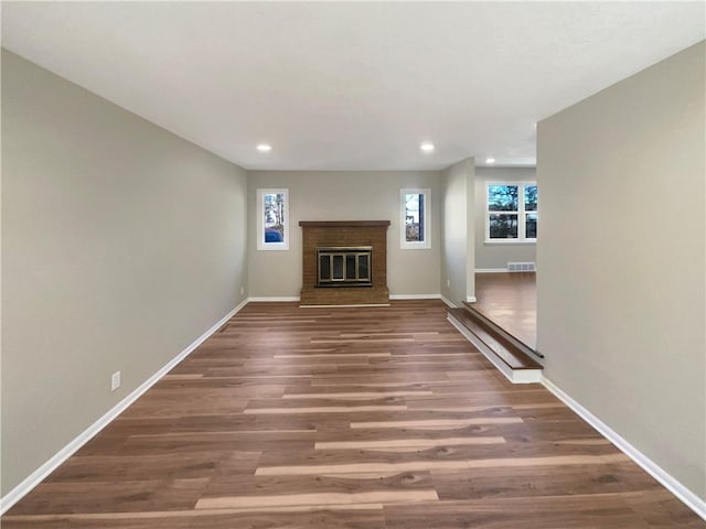 unfurnished living room with a fireplace, baseboards, wood finished floors, and recessed lighting