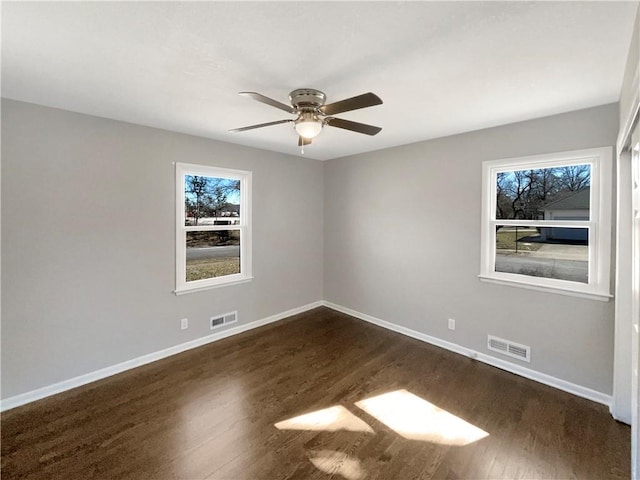 spare room featuring baseboards, visible vents, and dark wood finished floors