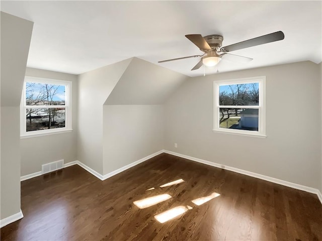 bonus room with lofted ceiling, ceiling fan, dark wood-style flooring, visible vents, and baseboards