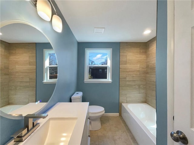 bathroom featuring toilet, a bathing tub, vanity, baseboards, and tile patterned floors