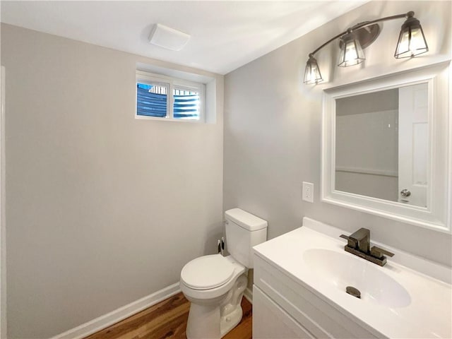 half bathroom featuring toilet, baseboards, wood finished floors, and vanity