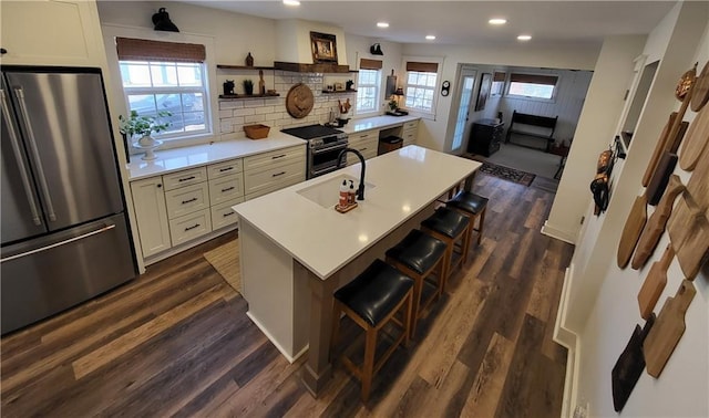 kitchen with a kitchen bar, open shelves, dark wood finished floors, stainless steel appliances, and light countertops