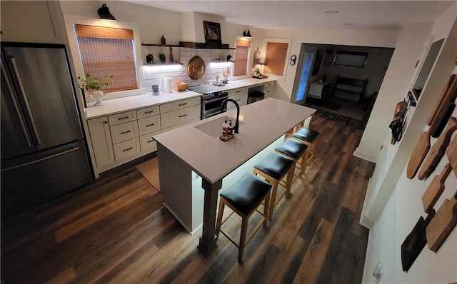 kitchen with a sink, a kitchen breakfast bar, dark wood-style floors, stainless steel appliances, and light countertops