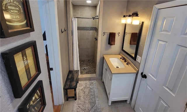 full bathroom featuring vanity, a textured wall, tile patterned flooring, and a tile shower