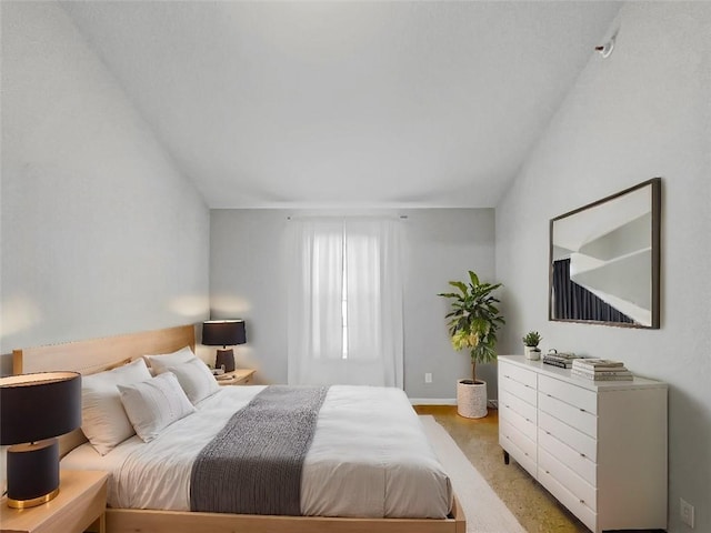 bedroom with lofted ceiling, light carpet, and baseboards