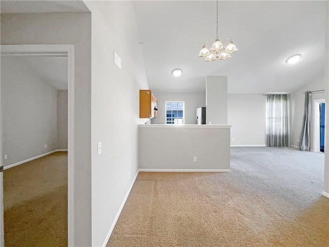 carpeted spare room featuring baseboards, an inviting chandelier, lofted ceiling, and a healthy amount of sunlight