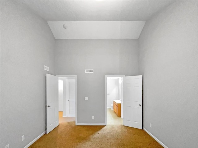 unfurnished bedroom with light carpet, high vaulted ceiling, visible vents, and baseboards