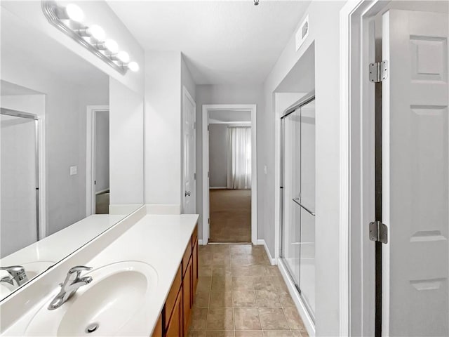 full bath featuring a stall shower, visible vents, vanity, and baseboards