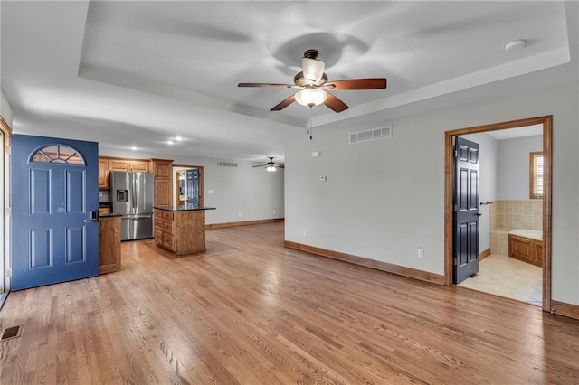 unfurnished living room featuring light wood-style floors, visible vents, and a tray ceiling