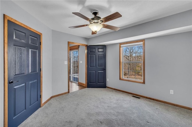 interior space with carpet flooring, ceiling fan, visible vents, and baseboards