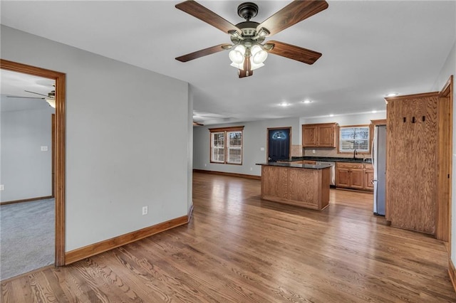 kitchen with appliances with stainless steel finishes, dark countertops, a healthy amount of sunlight, and light wood-style floors