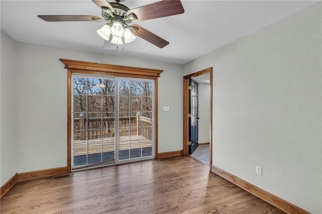 empty room featuring a ceiling fan, baseboards, visible vents, and wood finished floors