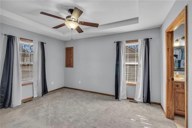 unfurnished room featuring light carpet, a ceiling fan, visible vents, baseboards, and a tray ceiling