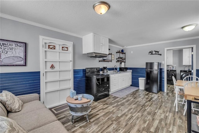 kitchen featuring a sink, a textured ceiling, washer and dryer, under cabinet range hood, and black appliances