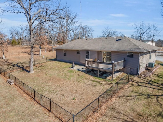 rear view of property featuring central air condition unit, a shingled roof, fence, a lawn, and a wooden deck