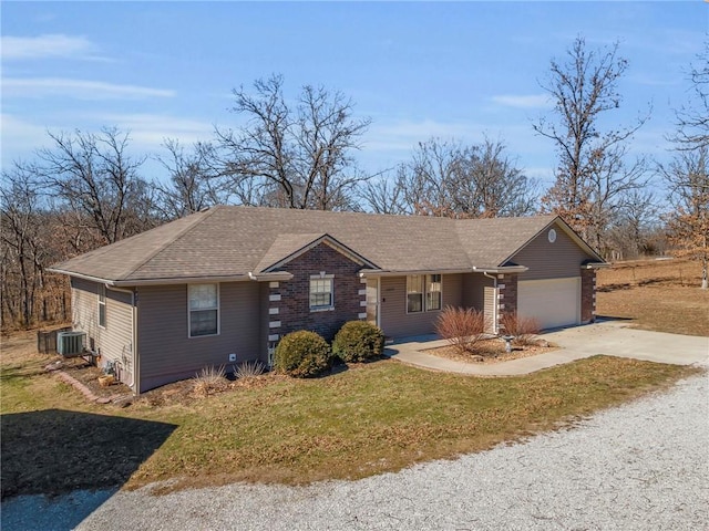 view of front of house with an attached garage, cooling unit, a shingled roof, concrete driveway, and a front yard