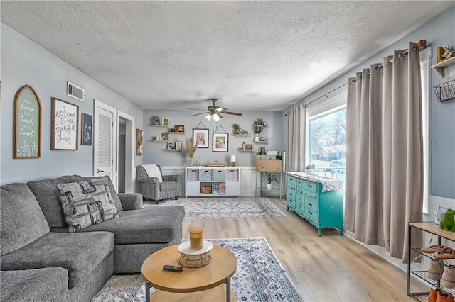 living room with visible vents, a textured ceiling, light wood-type flooring, and ceiling fan