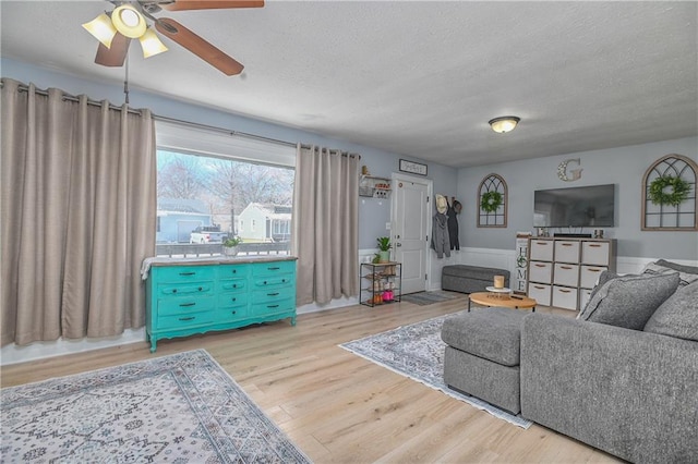 living room featuring ceiling fan, a textured ceiling, and wood finished floors