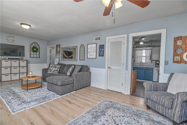 living area with visible vents, a textured ceiling, and wood finished floors