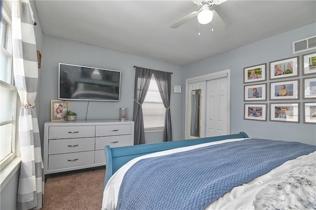 bedroom with a closet, a ceiling fan, visible vents, and dark carpet