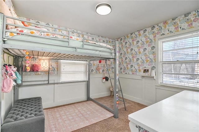 bedroom featuring multiple windows, carpet floors, wainscoting, and wallpapered walls