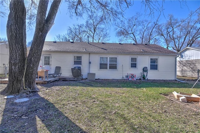 rear view of house with a fire pit, a lawn, a deck, and fence