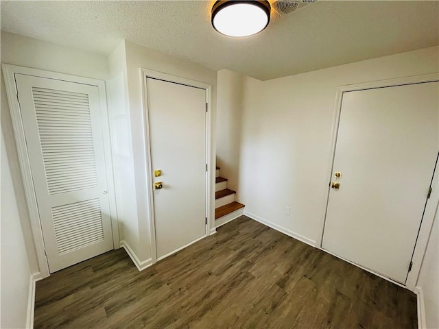 entryway with visible vents, a textured ceiling, stairs, and dark wood-style flooring