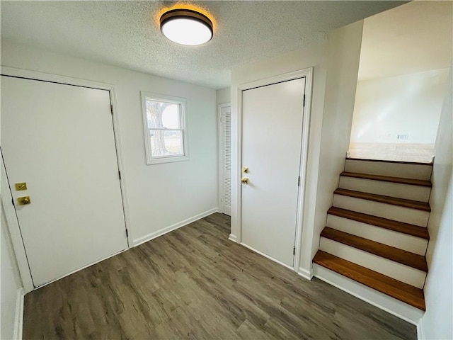 entrance foyer featuring stairway, baseboards, a textured ceiling, and wood finished floors