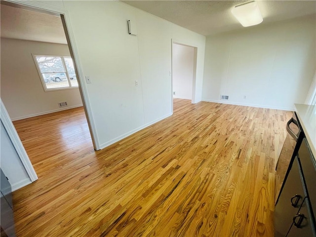 empty room with visible vents, light wood-type flooring, and baseboards