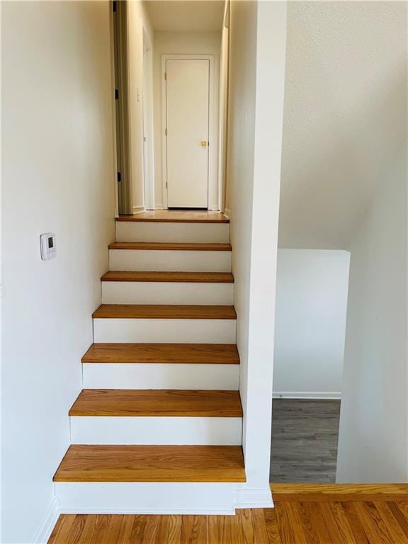 staircase with baseboards and wood finished floors