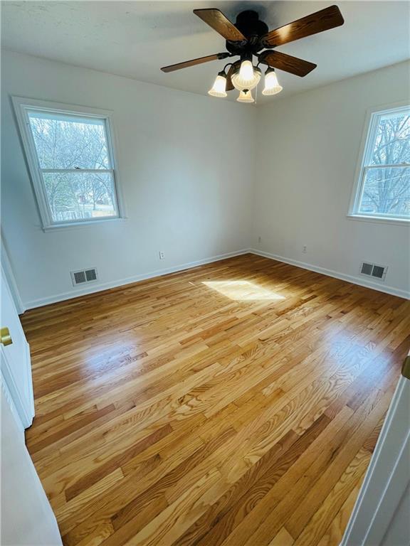 spare room featuring light wood-type flooring, visible vents, baseboards, and ceiling fan