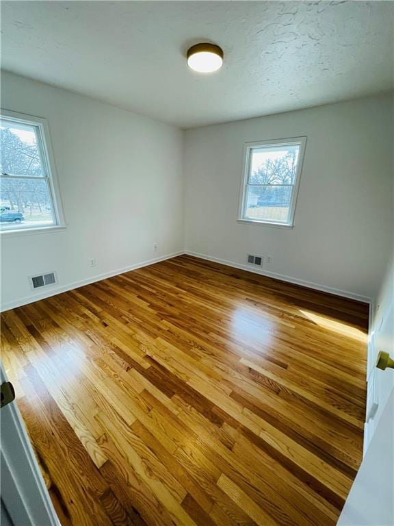 unfurnished room featuring visible vents, baseboards, and wood finished floors