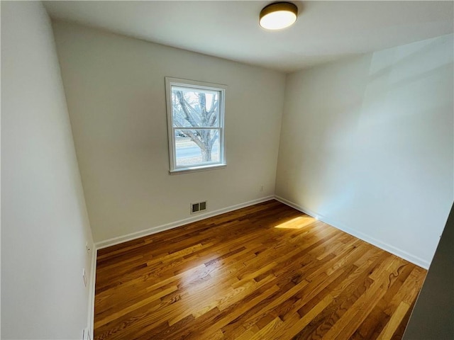 spare room featuring visible vents, baseboards, and wood finished floors