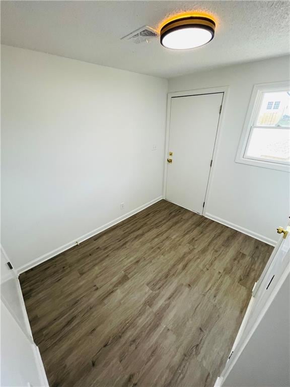 spare room with visible vents, baseboards, a textured ceiling, and wood finished floors